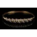 A 9ct gold and diamond oval hinged bangle, the front mounted with rows of circular cut diamonds in a