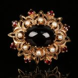 A 9ct gold, carbuncle garnet and cultured pearl brooch in a pierced oval design, mounted with the