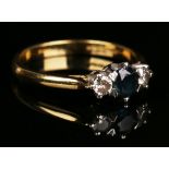 An 18ct gold, sapphire and diamond three stone ring, claw set with the circular cut sapphire between