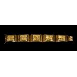 A gold bracelet, formed as a row of five curved rectangular panels depicting South American style