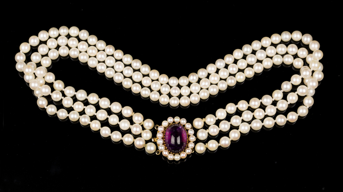 A three row collar necklace of uniform cultured pearls on a gold, cabochon amethyst and cultured