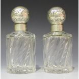 A pair of German .800 silver cylindrical glass perfume bottles, each silver top decorated in