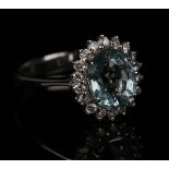 An 18ct white gold, aquamarine and diamond cluster ring, claw set with an oval cut aquamarine within