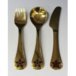 A Georg Jensen sterling silver gilt knife, fork and spoon, each terminal decorated with a red and
