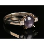 A diamond and star sapphire three stone ring, claw set with the oval star sapphire between two