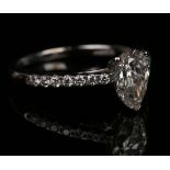 An 18ct white gold and diamond ring, claw set with the principal pear shaped diamond between diamond
