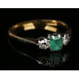 A gold, emerald and diamond three stone ring, claw set with the rectangular cut emerald between