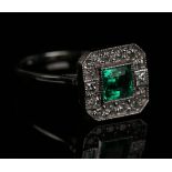 A white gold, emerald and diamond square cluster ring, mounted with the central emerald between