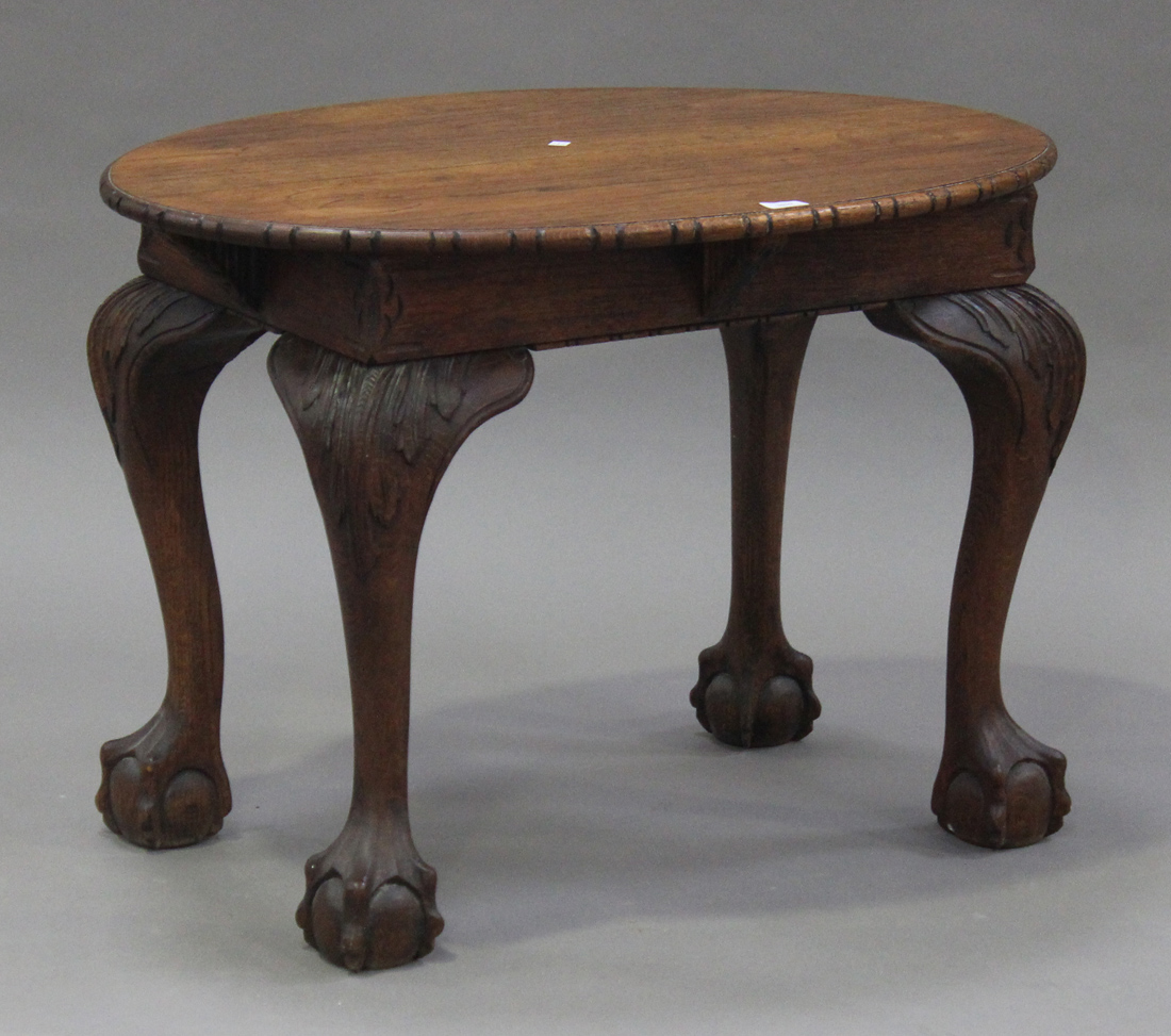 An early 20th century oak oval occasional table, the top raised on carved acanthus leaf cabriole