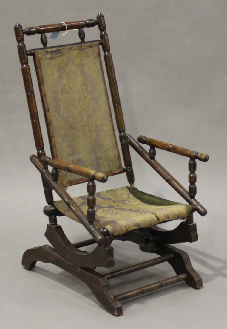 A late Victorian stained walnut rocking chair of turned construction, raised on a spring seat,