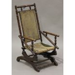 A late Victorian stained walnut rocking chair of turned construction, raised on a spring seat,