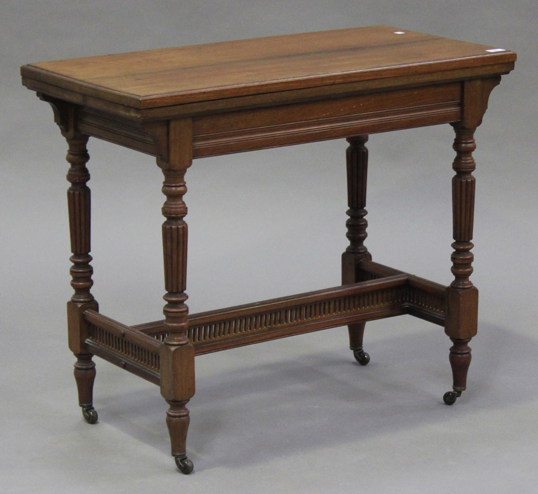 A late Victorian walnut rectangular fold-over card table, the hinged top on turned and reeded