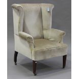 An Edwardian wing back armchair, upholstered in velour, raised on square tapering legs and china