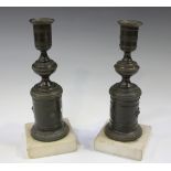 A pair of Regency brown patinated cast bronze candlesticks with knop stems and cylindrical bases