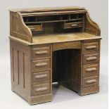An early 20th century oak roll-top twin pedestal desk, the tambour front revealing a fitted interior