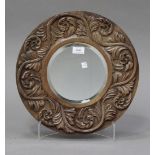 A 20th century carved walnut circular wall mirror, the bevelled plate within a foliate frame,