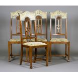 A set of four Edwardian Arts and Crafts oak dining chairs, the arched backs with carved and