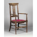 An Edwardian Arts and Crafts oak elbow chair, possibly by Wylie & Lochhead, the carved bar back