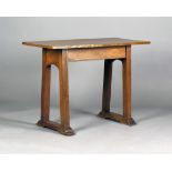 An Edwardian Arts and Crafts oak side table, the rectangular top on block legs united by shaped