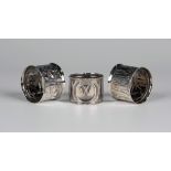 A pair of Arts and Crafts silver napkin rings, each decorated in relief with stylized foliate panels