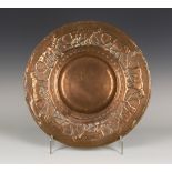 An early 20th century Arts and Crafts copper charger of circular form, the raised border worked with