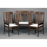 An early 20th century Arts and Crafts oak three-piece suite, comprising a settee and a pair of