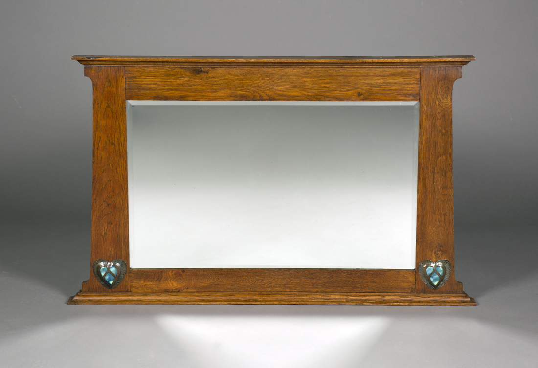 An Edwardian Arts and Crafts oak overmantel mirror, possibly retailed by Liberty & Co, the