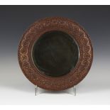 An Edwardian Arts and Crafts oak framed circular wall mirror, the bevelled plate within a continuous