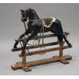 An early/mid-20th Century black painted wooden rocking horse with later saddle and reins, on a