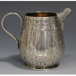 A Victorian silver cream jug of ovoid form, engraved with vertical flower filled and vacant oval