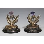 A pair of George V silver menu holders, each in the form of a thistle stem on a circular foot raised