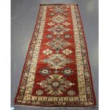 An Afghan runner, late 20th century, the chestnut field with six shaped polychrome medallions,