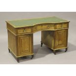 An Edwardian oak twin pedestal desk, the moulded top with a concave centre, fitted with three frieze