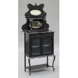 A late Victorian ebonized display cabinet, the mirrored shelf back above a pair of glazed doors,