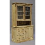 An early 20th century stripped pine kitchen cabinet, the glazed top above an arrangement of