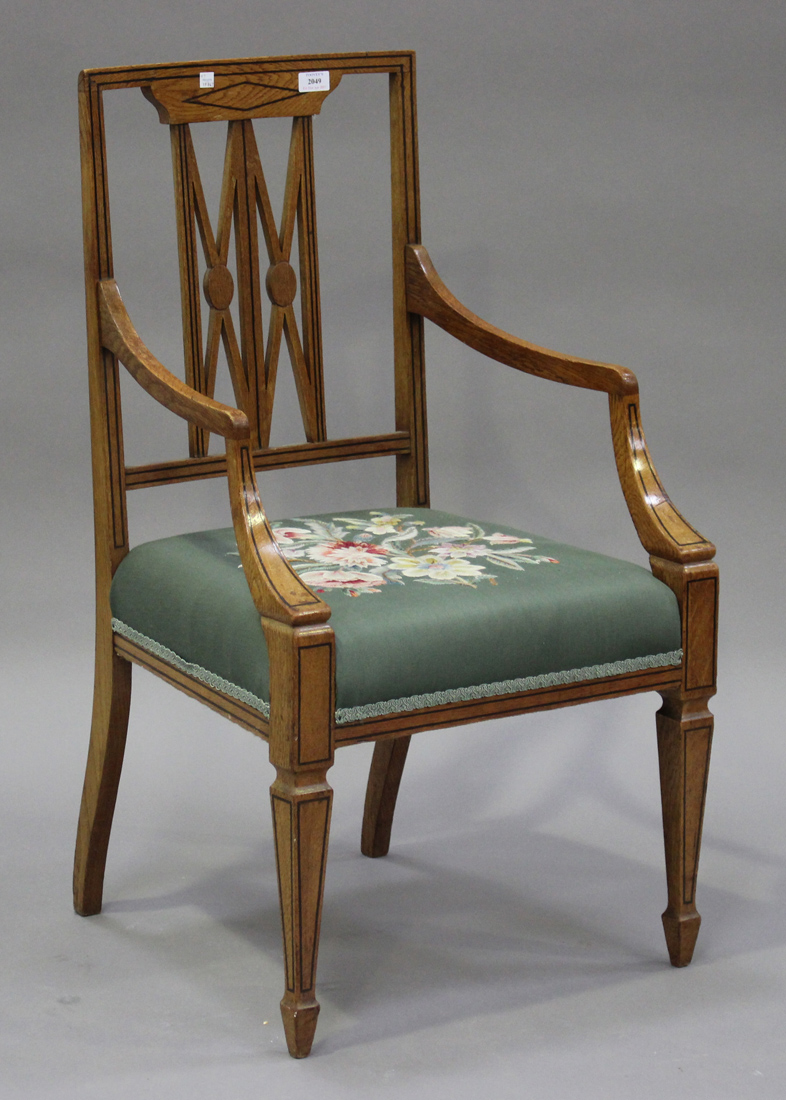 An early 20th century oak armchair with floral needlework seat, raised on square tapering legs,