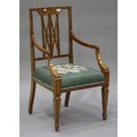 An early 20th century oak armchair with floral needlework seat, raised on square tapering legs,