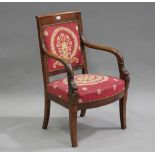 An early 19th century mahogany open armchair, the upholstered seat and back flanked by carved