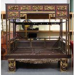 An early/mid-20th century Chinese painted and giltwood opium bed, the canopy with red painted and