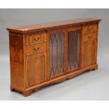 A 20th century reproduction yew sideboard, the glazed central section flanked by drawers and