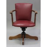 A 20th century reproduction swivel office chair with red leather seat and back, on outswept legs,