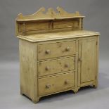 An early 20th century stripped pine side cabinet, the shelf back above three drawers and a cupboard,