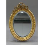 An early 20th century oval gilt framed wall mirror with ribbon surmount, 72cm x 50cm. Buyer’s