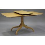 A 20th century reproduction pale hardwood extending dining table with a single extra leaf, raised on