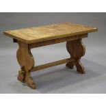 A 20th century oak kitchen table, the rectangular top raised on shaped supports united by a