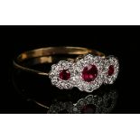 A gold, ruby and diamond ring in a triple cluster design, mounted with three circular cut rubies,