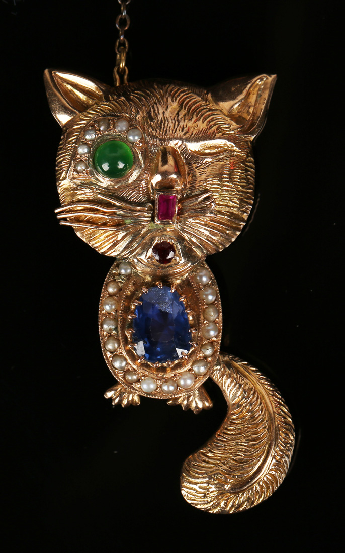 A gold, sapphire, seed pearl, garnet and gem set brooch, designed as a caricature of a cat, detailed