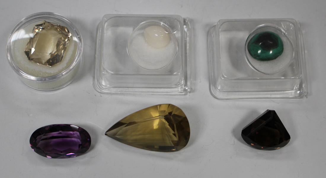 Four unmounted faceted gemstones, including amethyst and smoky quartz, an unmounted opal and an