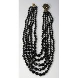 A five row necklace of graduated faceted black glass beads on a gilt metal and black paste clasp.