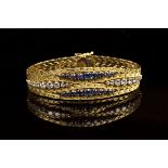 A gold, diamond and sapphire bracelet in a textured tapering interwoven link design, the front